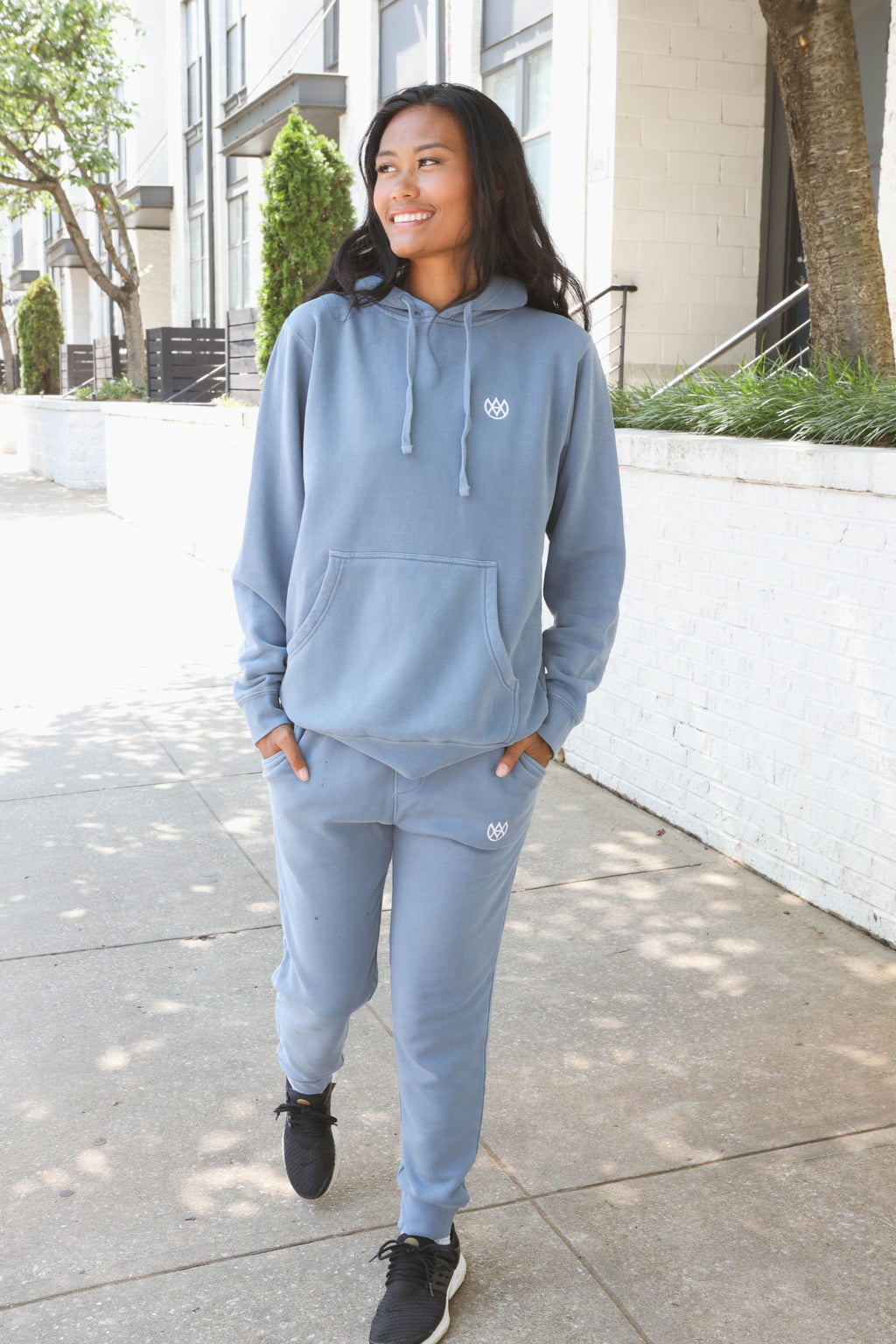 Woman wearing a blue tracksuit with a logo on a sidewalk