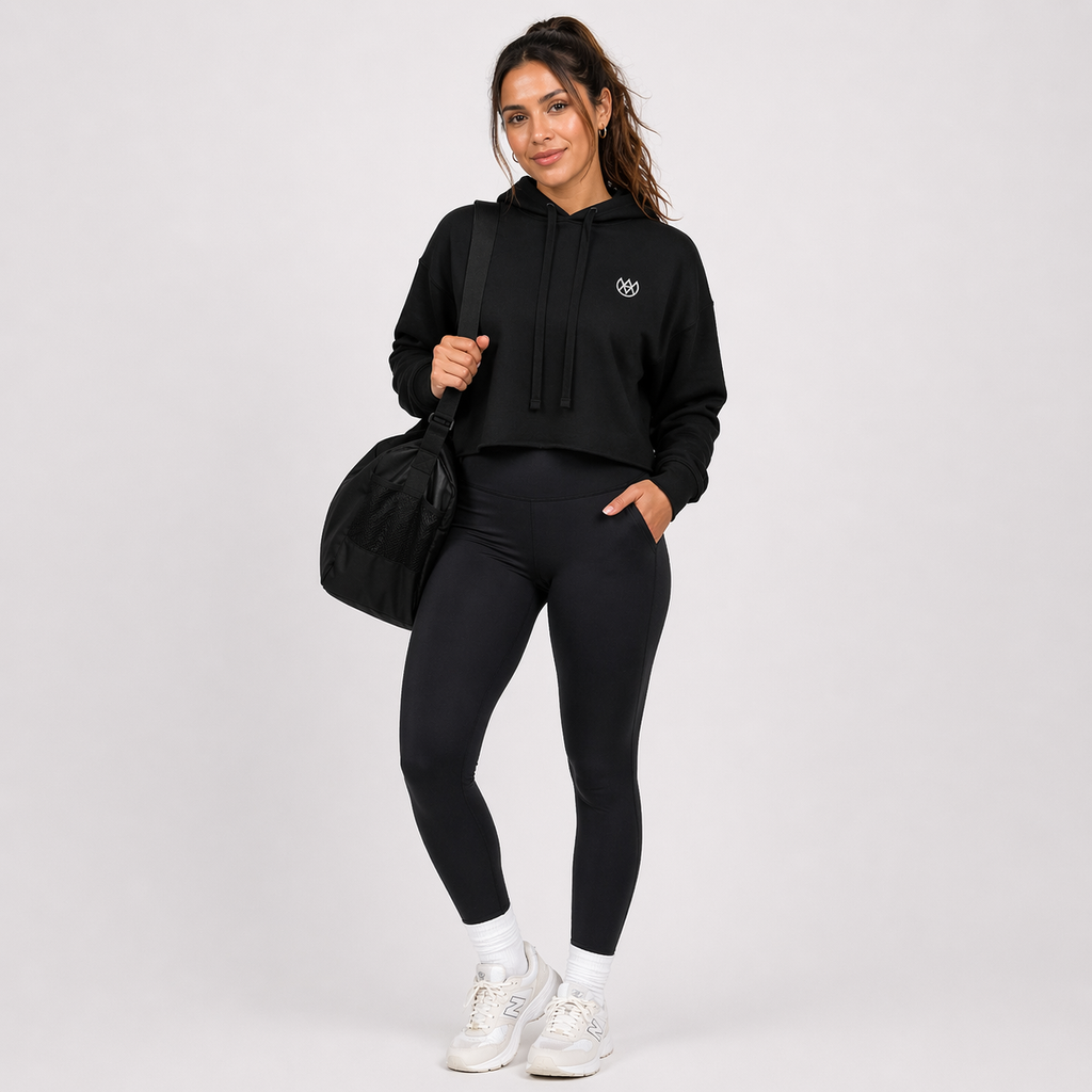Woman wearing a black hoodie and leggings with a duffel bag on a white background
