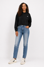 Woman wearing a black hoodie and blue jeans on a white background