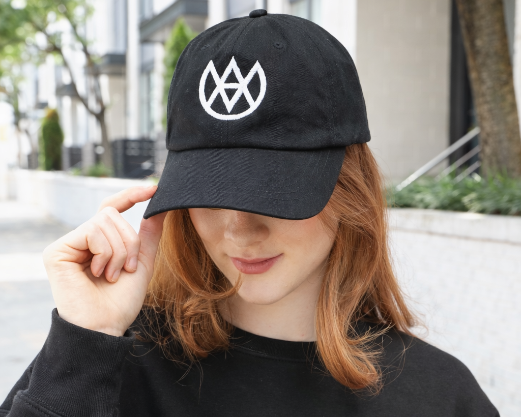 Person wearing a black cap with a white logo outdoors