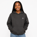Woman wearing a black hoodie with a small logo on a white background
