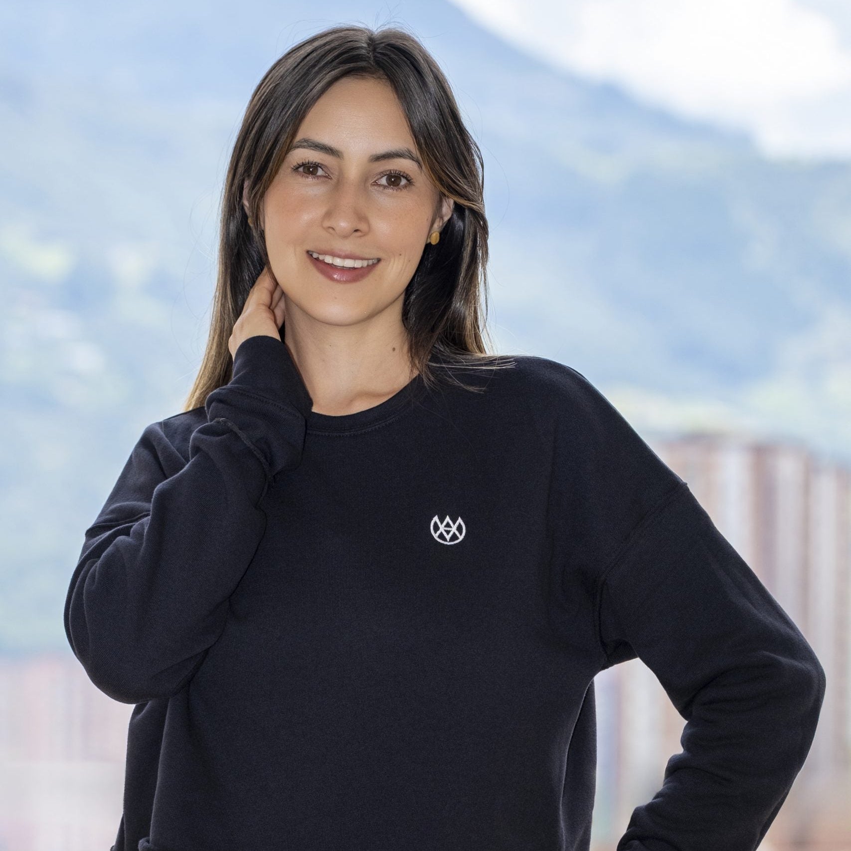 Woman wearing a black sweatshirt with a logo against a blurred indoor background