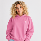 Woman wearing a pink hoodie with a small logo on a light gray background