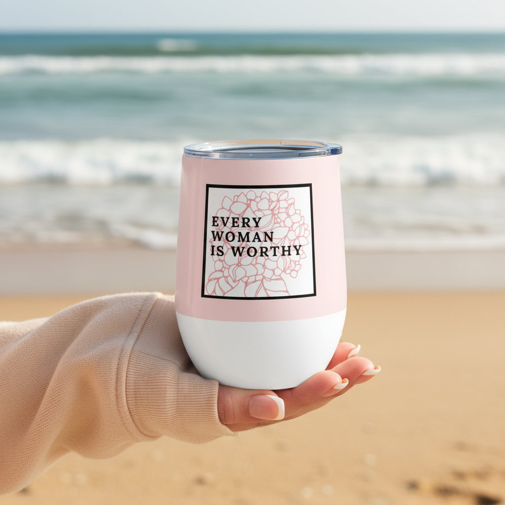 Person holding a pink and white tumbler with 'Every Woman is Worthy' text